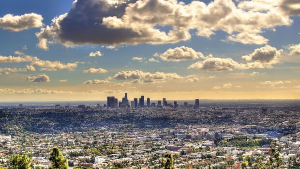A panoramic view of Los Angeles skyline with clouds above the cityscape visible in the distance