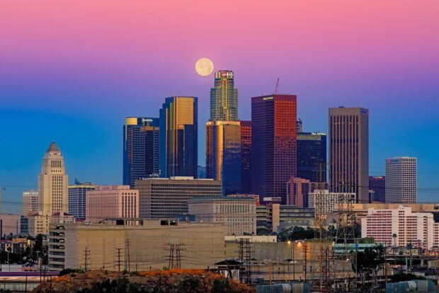 Los Angeles skyline with full moon over high rise buildings at dusk