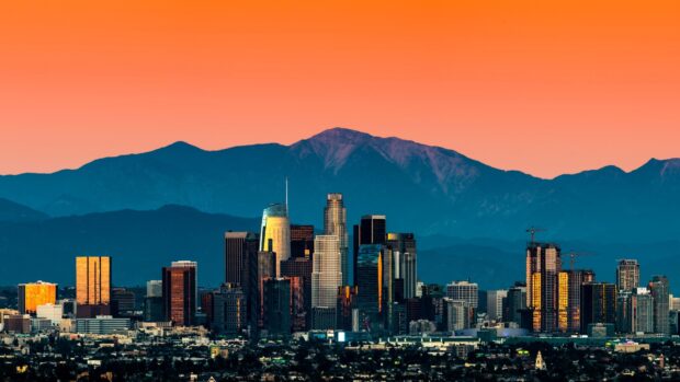 Los Angeles skyline with mountain backdrop under a colorful sunset sky
