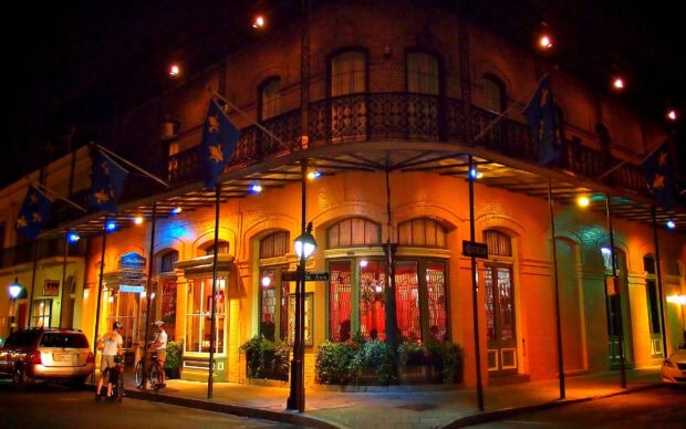 Historic street corner in Louisiana with cyclists and illuminated building facade at night