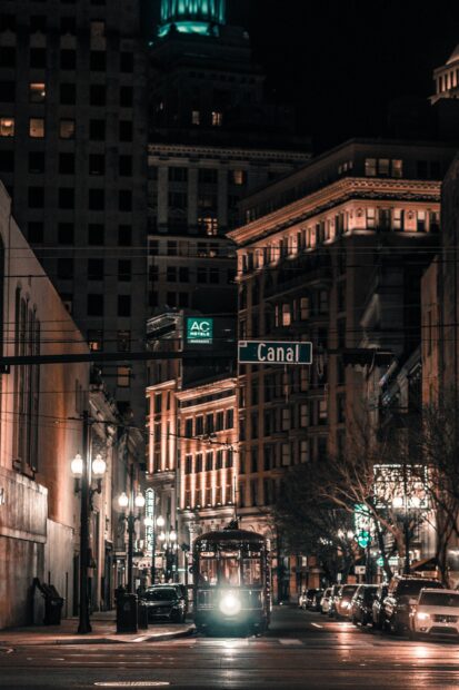 Streetcar moving through a Louisiana city street at night under a Canal street sign