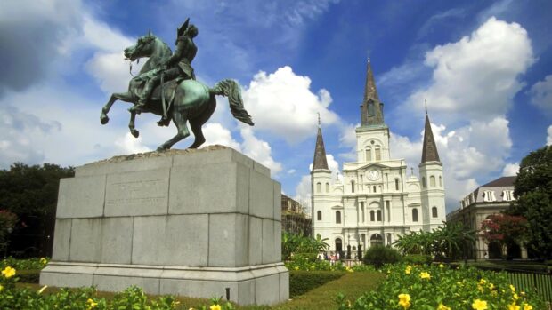 A statue of a rider on horseback in Louisiana alongside a historic cathedral under a blue sky