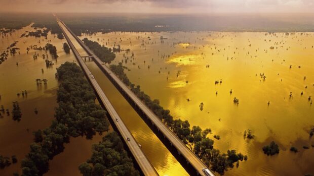 Aerial view of a Louisiana highway crossing through flooded forest areas at sunset