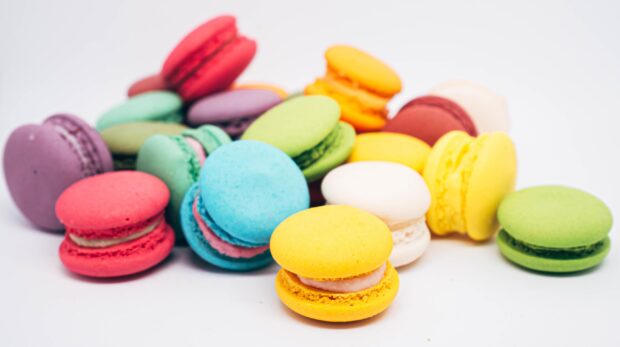 A colorful assortment of macaron sweets arranged on a white surface with a soft focus background