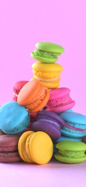 A colorful stack of macaron with various flavors on a pink background