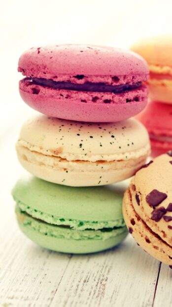 A close up of colorful macaron stacked on a wooden surface showcasing various flavors