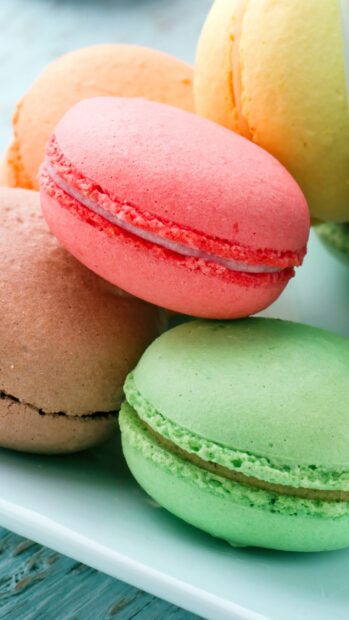 A close up of colorful macaron stacked together on a plate
