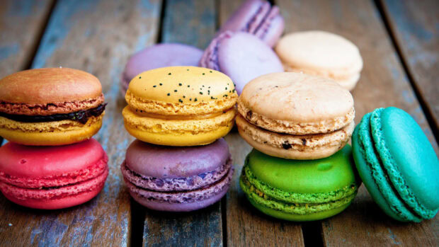 Colorful macaron assortment stacked on rustic wooden surface in vibrant closeup