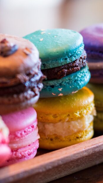 Colorful macaron close up showing various delicious macaron flavors in a wooden tray