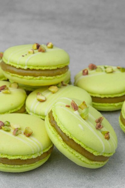 Green macaron with pistachio nuts decoration on top of several macarons