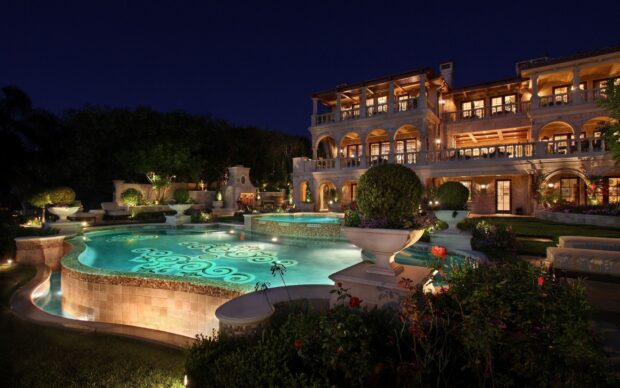 Luxury mansion with illuminated swimming pool and garden at night