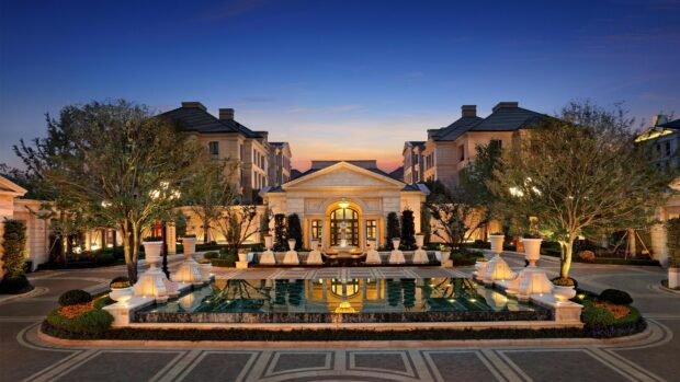 Luxurious mansion with elegant architecture and a large reflecting pool at dusk