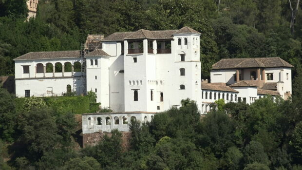 A historic mansion surrounded by lush green trees and vegetation