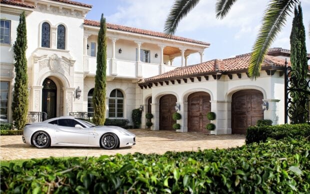 Luxury mansion with elegant architecture and tall cypress trees in front of the driveway