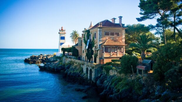 Mansion surrounded by lush greenery on rocky coastline