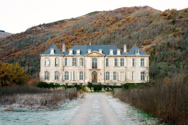 Large mansion surrounded by frosty grass and autumn trees in a mountainous area