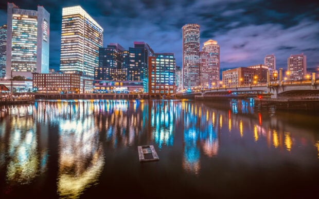 Night view of Massachusetts city skyline reflecting on calm river water