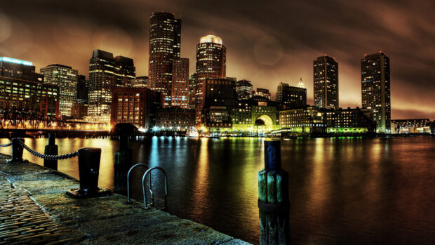 Nighttime Massachusetts cityscape with illuminated skyline and waterfront reflections