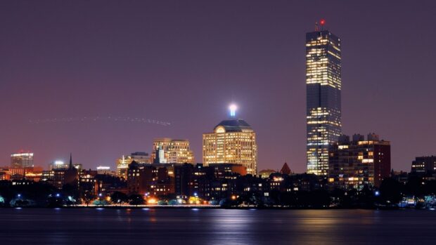 Night cityscape of Massachusetts skyline with illuminated buildings and calm water