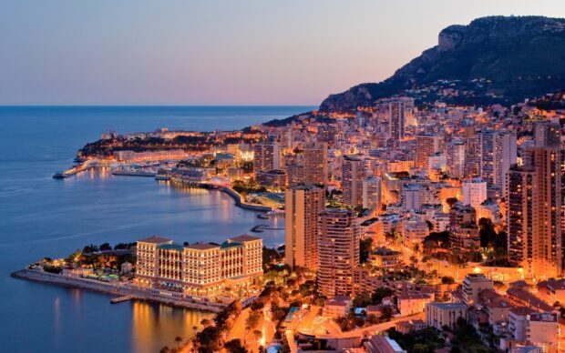 A stunning Monaco cityscape with illuminated buildings by the coastline at dusk