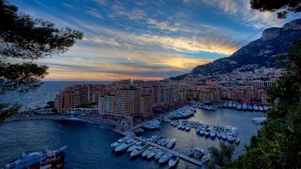 Scenic Monaco harbor view with luxury yachts and residential buildings at sunset