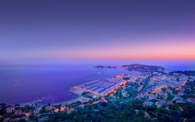 Scenic view of Monaco coastline with harbor and illuminated city at dusk