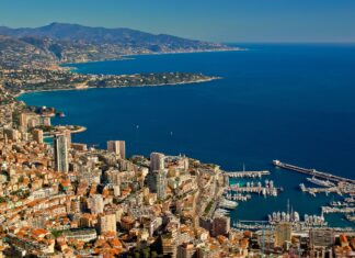 A panoramic view of Monaco city and its marina with the Mediterranean Sea and mountains in the background