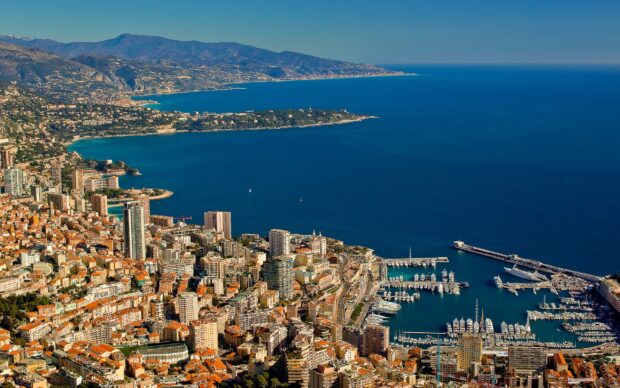 A panoramic view of Monaco city and its marina with the Mediterranean Sea and mountains in the background