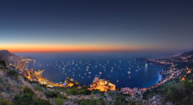 Stunning panoramic view of Monaco coast with yachts and city lights at twilight