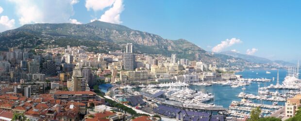 A panoramic view of Monaco cityscape with boats and mountains in the background