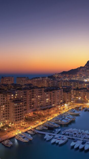 Sunset over Monaco marina with yachts and cityscape in warm evening light