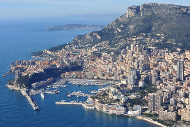A panoramic view of Monaco cityscape with coastal cliffs and marina filled with yachts