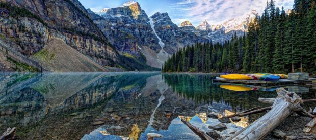 Moraine Lake natural landscape with vibrant trees and colorful canoes by the rocky mountains