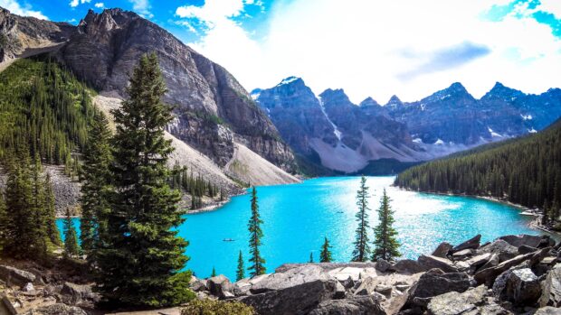 Moraine Lake with clear blue water and evergreen trees surrounded by towering mountain peaks
