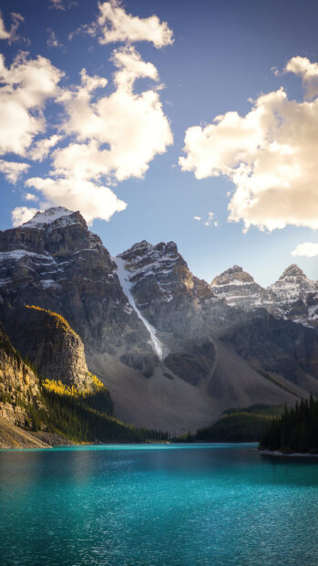 Turquoise Moraine Lake surrounded by mountains and forest under cloudy sky