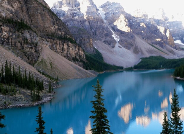 Moraine Lake reflecting surrounding mountains and forests in a clear blue scene