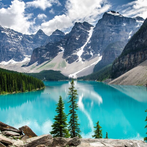 Turquoise waters of Moraine Lake surrounded by towering mountains and evergreen trees