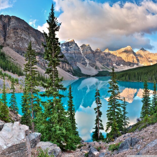 Evergreen trees and rugged mountains around Moraine Lake in a clear mountain landscape