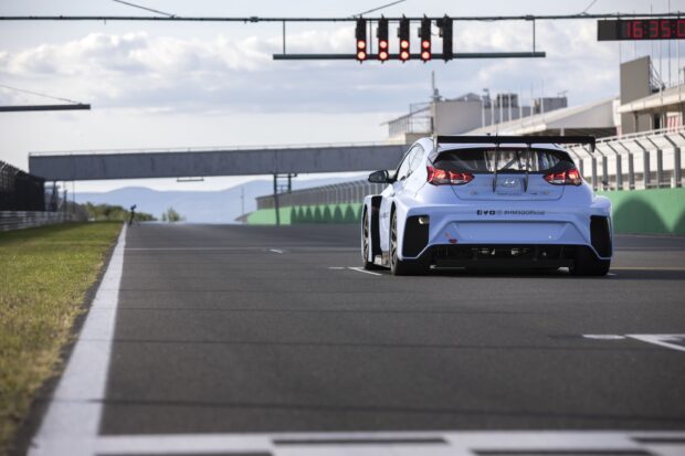 A racing car on a motorsport track during a race start with red lights visible above the car