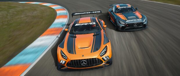 Two Mercedes AMG racing cars speeding on a racetrack with orange and black design