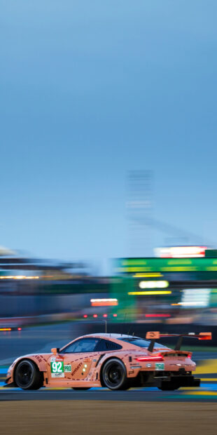 A pink racing car with number 92 speeding on the motorsports track during a race
