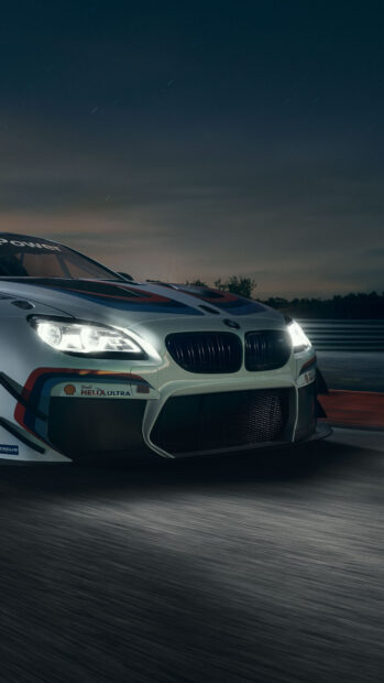 A close up of a BMW race car speeding on a night track in a motorsports event