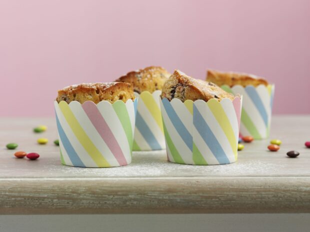 Muffin cupcakes baked in colorful striped paper cups on a wooden surface
