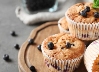 Blueberry muffin with fresh berries on a wooden tray