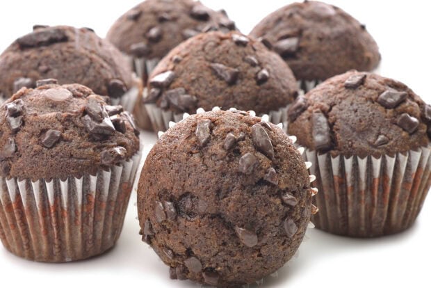 Chocolate muffin with chocolate chunks on a white surface arranged closely together