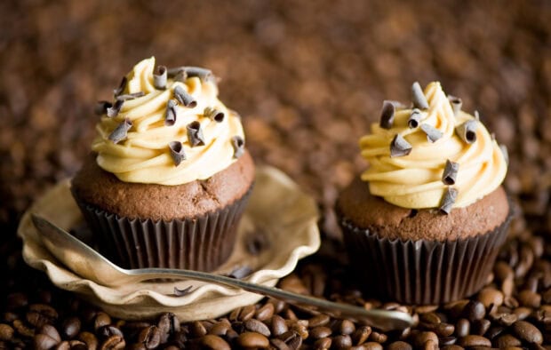 Two chocolate muffins with cream and chocolate curls on coffee beans