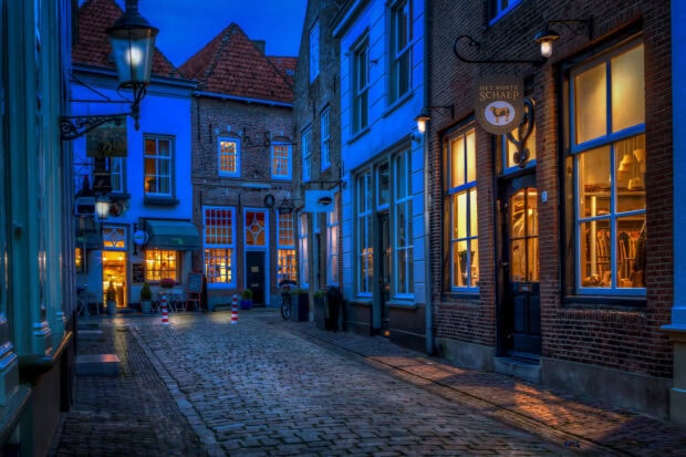Charming old Netherlands street with illuminated windows and cobblestone pavement at dusk