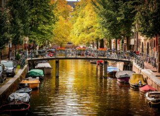 A peaceful canal with autumn trees and parked boats in the city of Netherlands