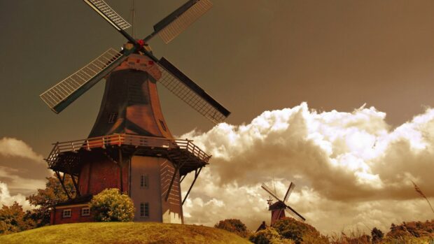 Historic Dutch windmill standing on a grassy hill under a dramatic sky in the Netherlands