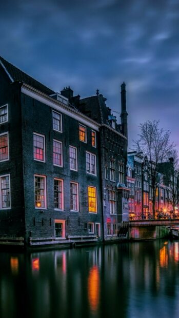 Historic canal houses in Netherlands reflecting on water at dusk with warm window lights